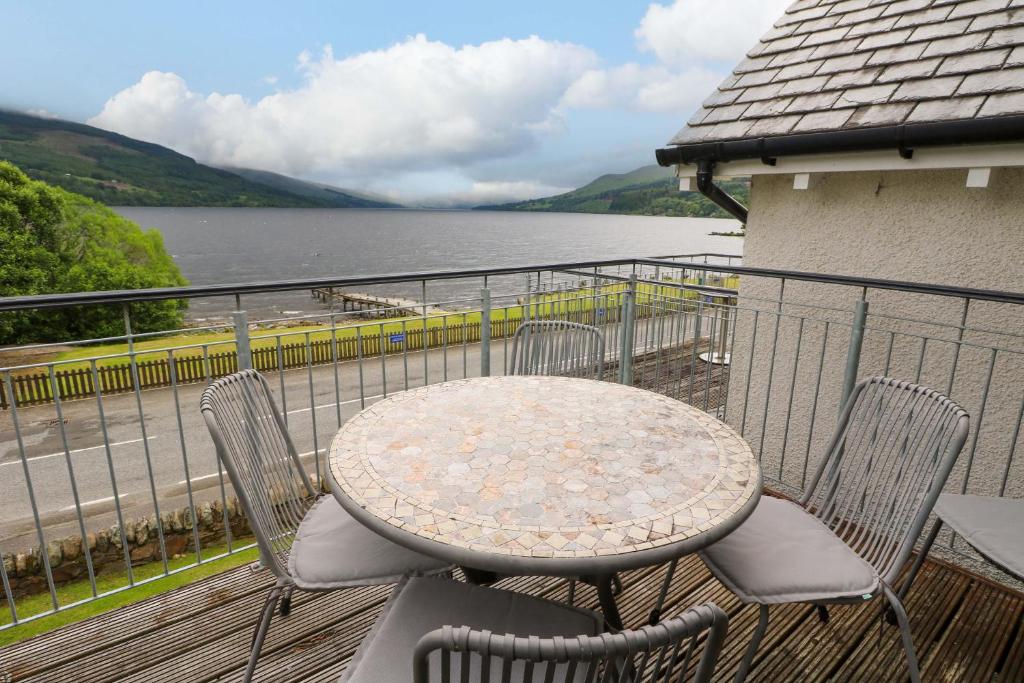 a table and chairs on a balcony with a view of a lake at Craigard in Aberfeldy