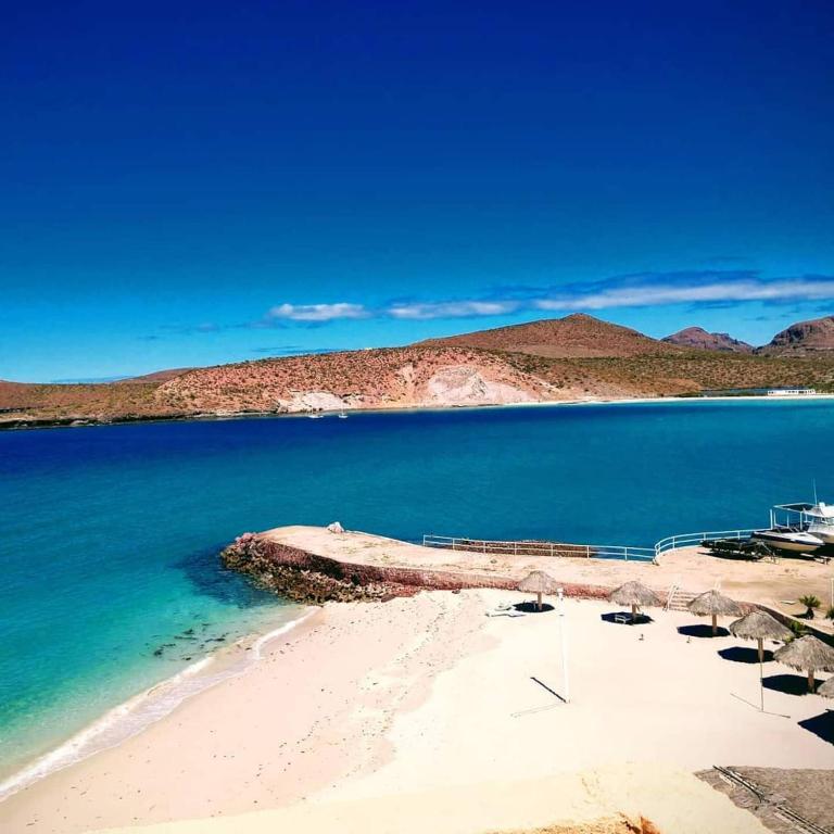 a beach with a boat in the water at Beach Condo 7- Upper Floor near Balandra fast WiFi in La Paz