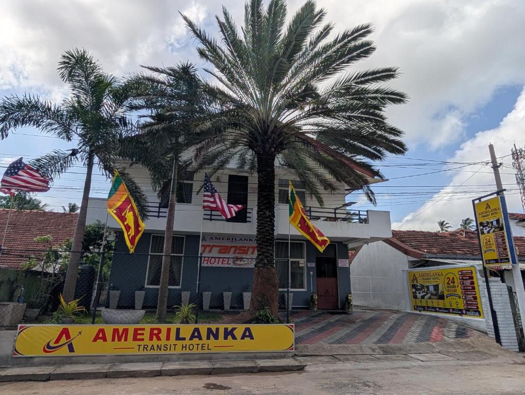 a palm tree in front of a building with flags at AmeriLanka Transit Hotel in Seeduwa