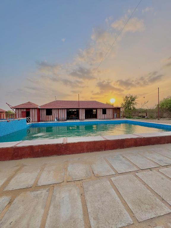 an empty swimming pool in front of a building at Jodhpur Farms in Jodhpur