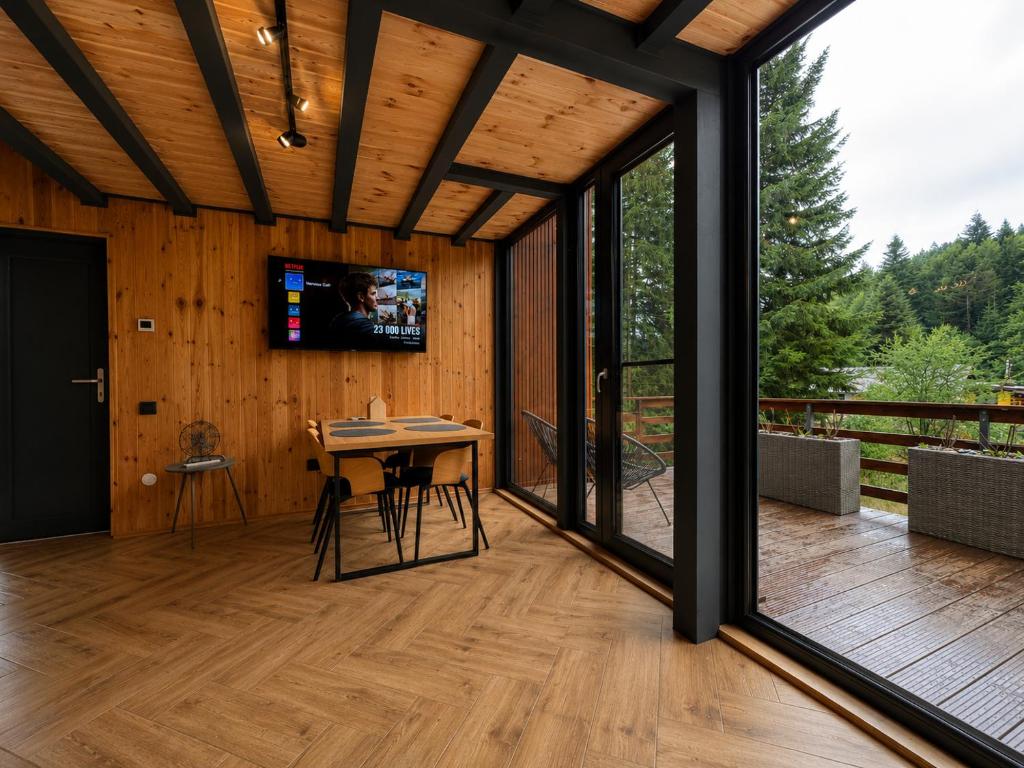 a screened porch with a table and a tv on the wall at Norway Cabins Sinaia Romantic Nordic Escape and Fire Pit in Sinaia
