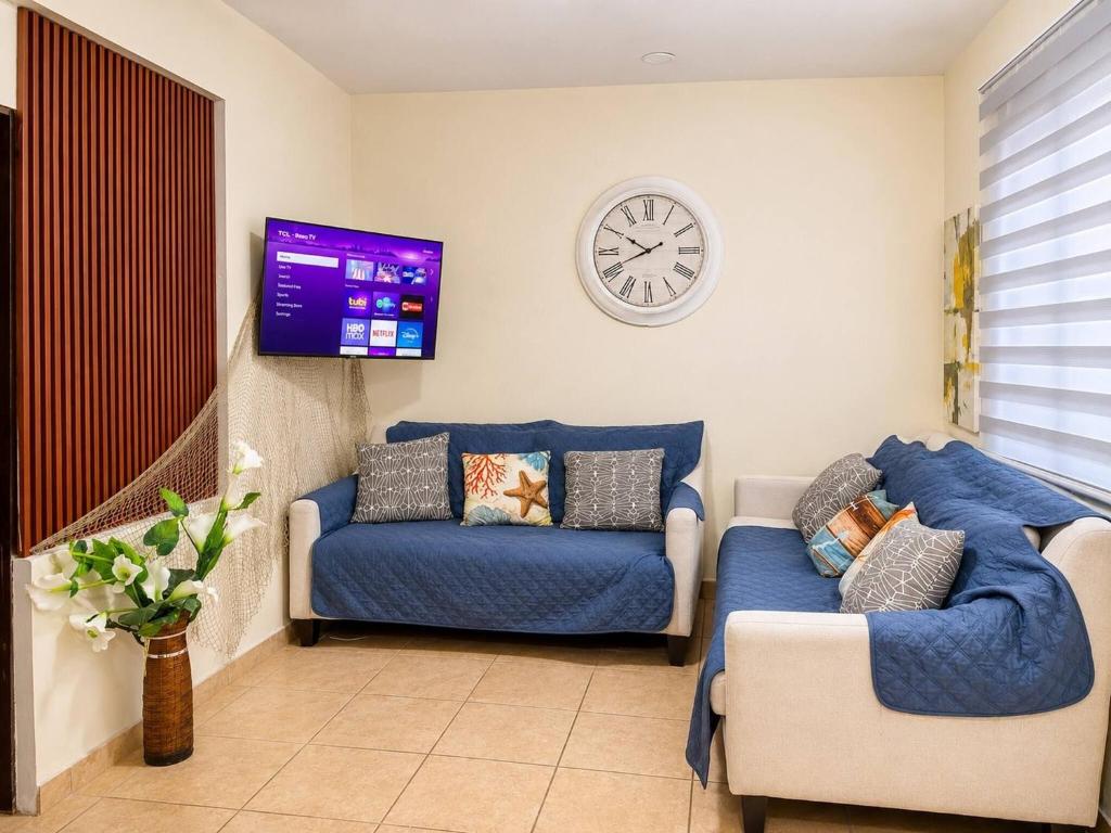 a living room with a couch and a clock on the wall at Los Flamboyanes Cozy Suite in Aguadilla