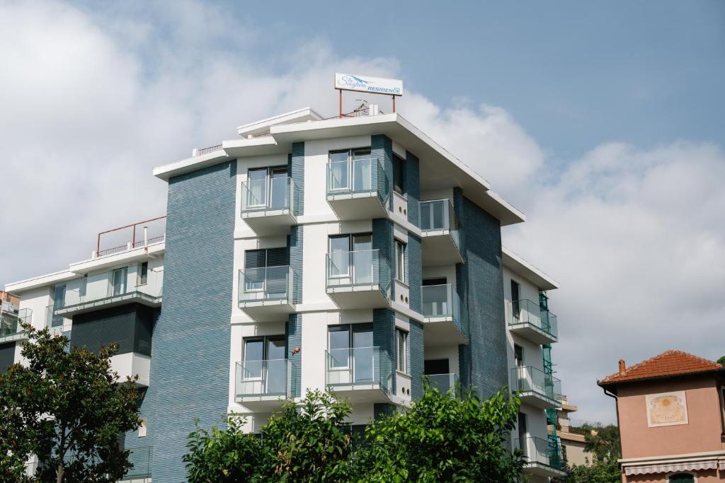 a tall apartment building with balconies and trees at Residence La Scogliera in Alassio