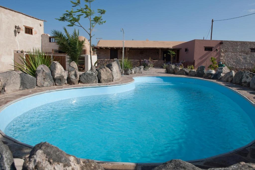 a large blue swimming pool with rocks around it at Canary House With Heated Pool in Tuineje