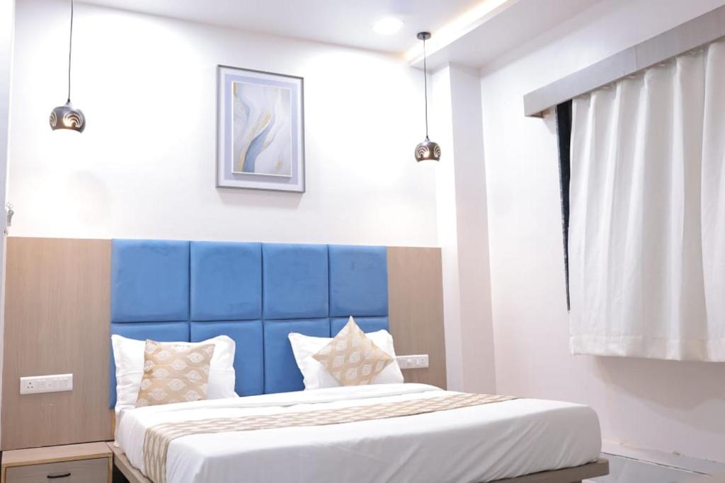 a bed with a blue headboard in a room at Hotel vs rooms in Ankleshwar