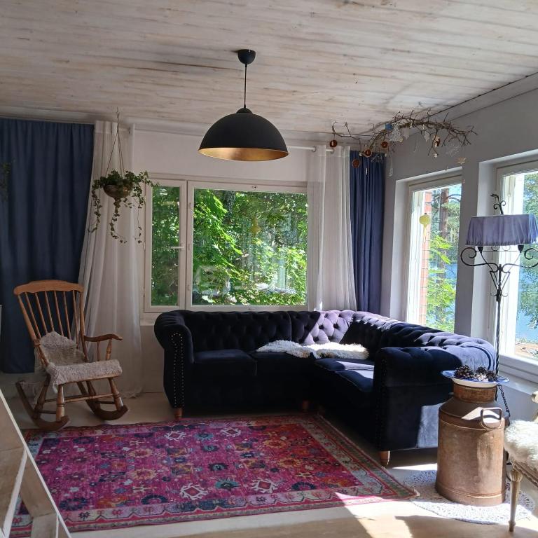 a living room with a black couch and windows at Suvela in Muurame
