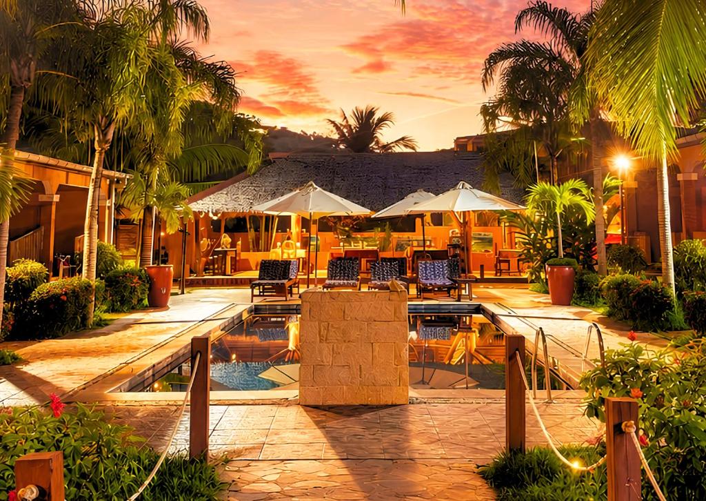 a resort with a pool and tables and umbrellas at Fleurs d'Ylang in Nosy Be