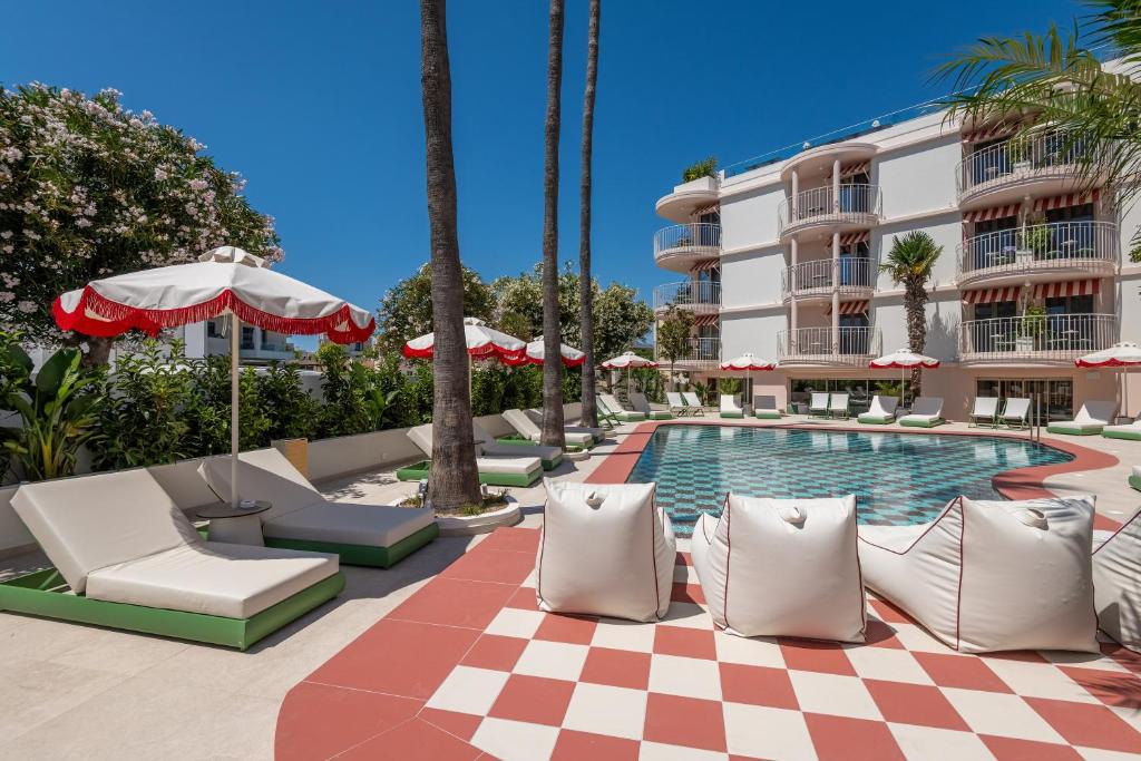 a pool with chairs and umbrellas next to a hotel at Villa Coo Boutique Hotel - Adults Only in Kos