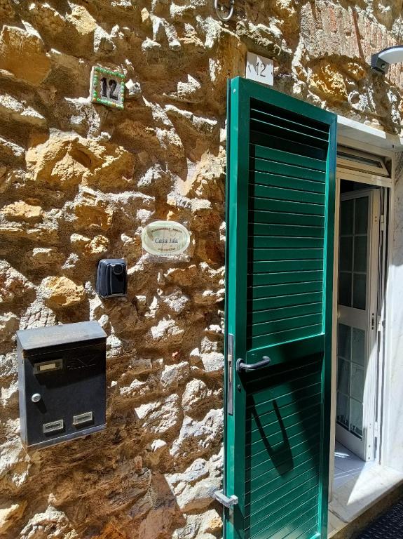 a stone wall with a green door and a mailbox at Casa Ida in Montemarcello