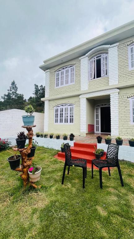 a house with a red table and chairs in the yard at Green Hills Cottage in Aravankādu