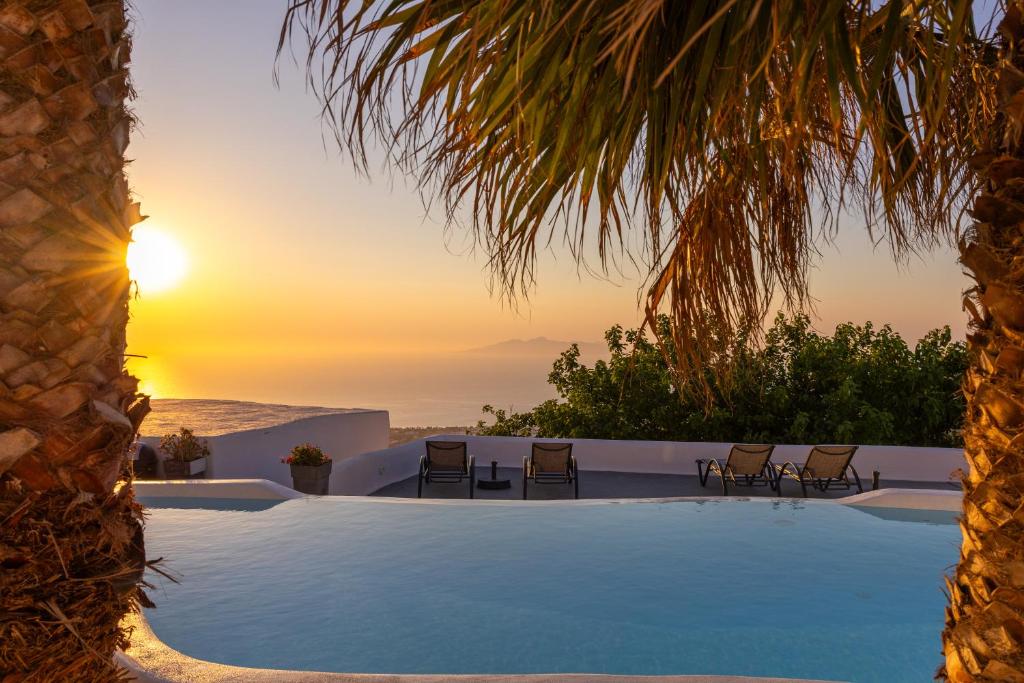 a pool with chairs and the sunset in the background at Loft Kaves Pool & Bar Suites in Pyrgos