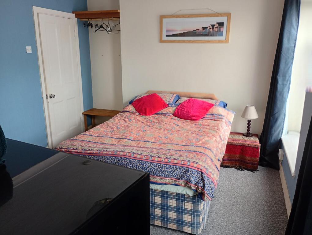 a bedroom with a bed with red pillows on it at House near beach in Port Talbot