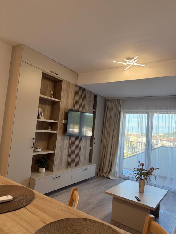 a living room with a table and a tv and a window at Urban Nest Florești in Floreşti