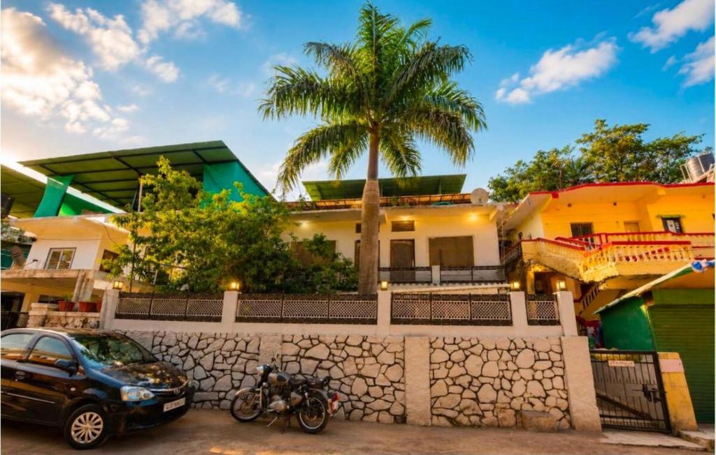 a car parked in front of a house with a palm tree at The Peach Boho in Mount Ābu