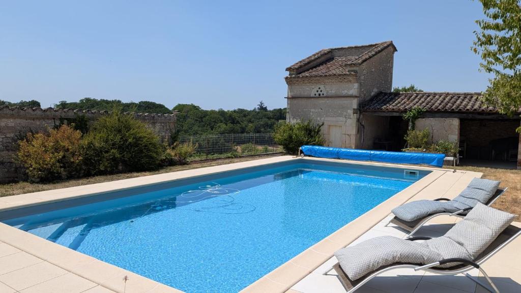 a swimming pool with chairs and a house at Grande chambre avec piscine in Villeneuve-sur-Vère
