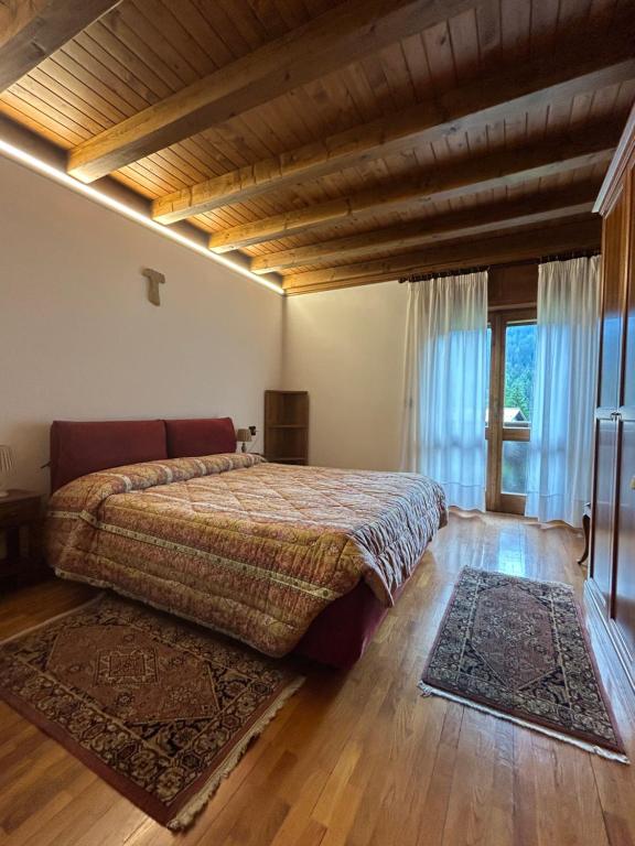 a bedroom with a large bed and a large window at Room Dolomites ''Antelao'' in San Vito di Cadore