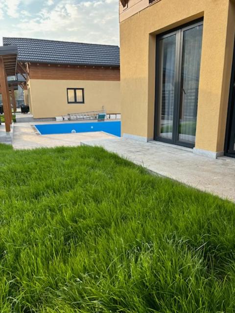 a house with a grassy yard next to a building at Zelena reka 4 in Vrhpolje