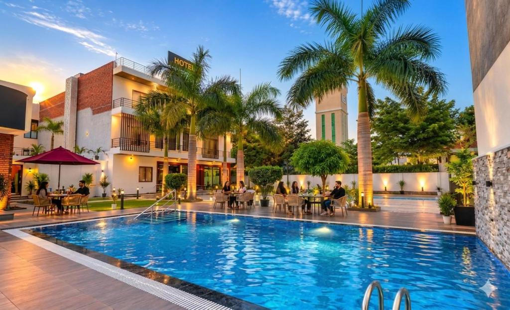 a pool at a hotel with people sitting around tables at Hotel Bella Vento Luxury Stay Near CGC Landran Mohali Chandigarh in Kharar