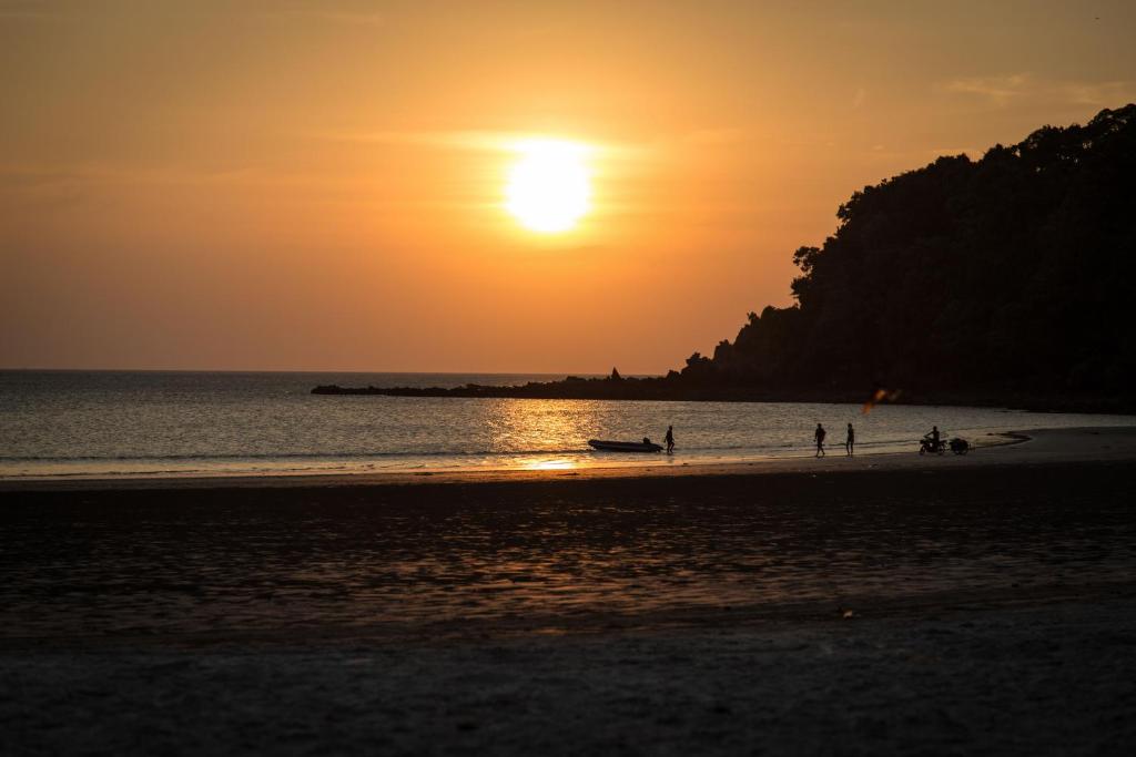 a group of people on the beach at sunset at Frog Garden Hut in Ko Phayam