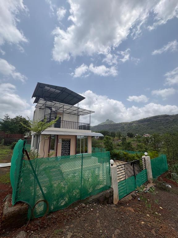 a light house with a green fence in front of it at kailasa Villa in Karjat