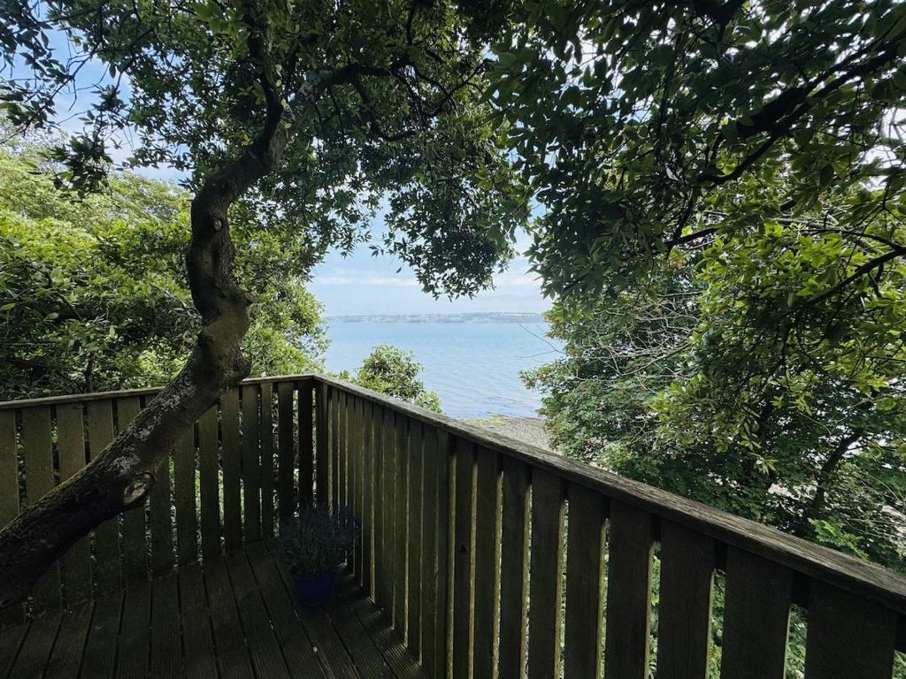 a wooden deck with a tree and a view of the ocean at Harbour view Tree House in Cobh