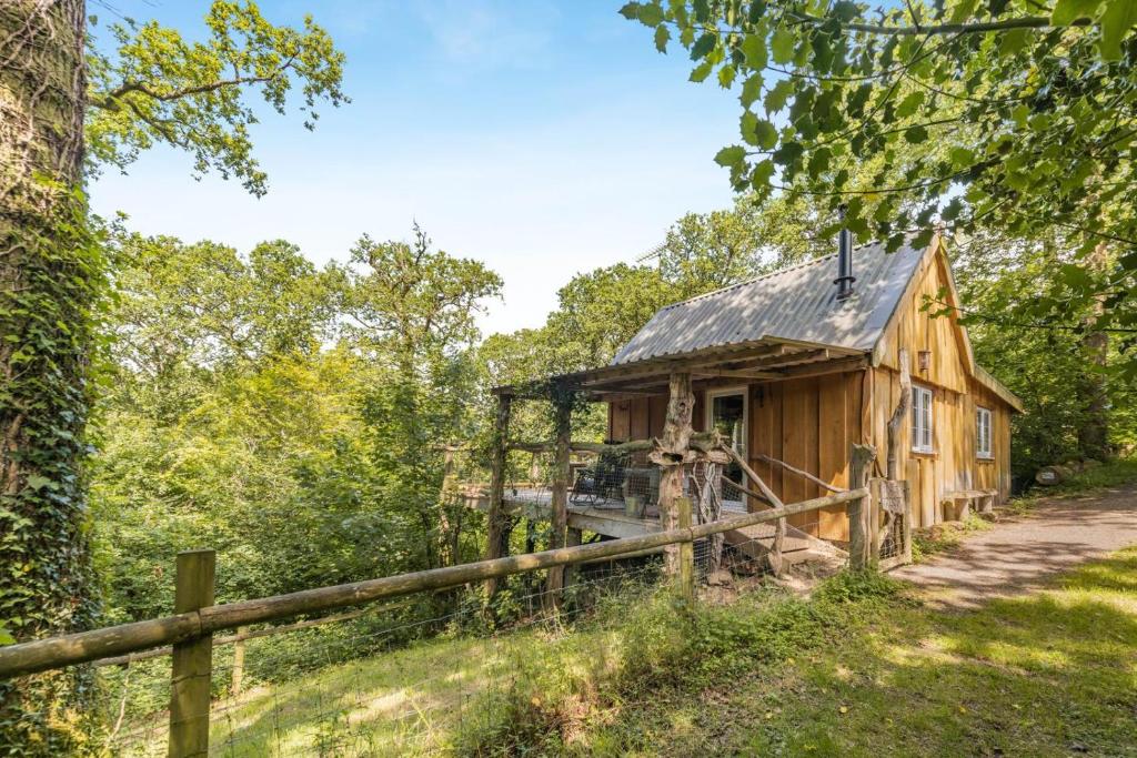 a wooden cabin in the woods with a fence at 1 Bed in Chulmleigh oc-74133 in Eggesford