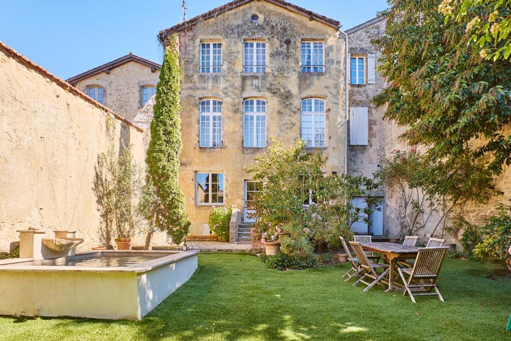 an old building with a table and chairs in a yard at Maison d'hôtes de charme Le Clos de la Cathédrale en Sud Gironde in Bazas