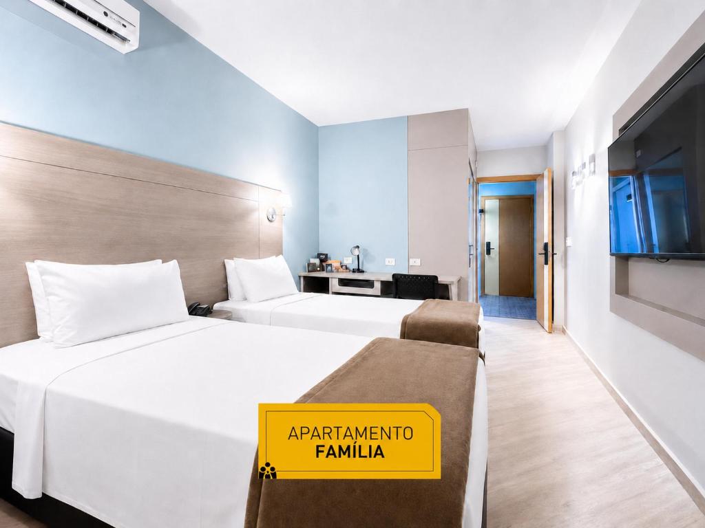 a hotel room with two beds and a yellow sign on it at Slim Hotel Curitiba Alto da XV in Curitiba