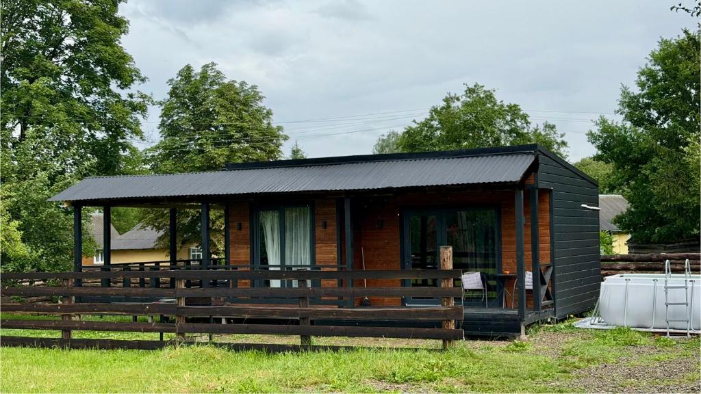 a small log cabin with a black roof at House Riverside in Kozmacz