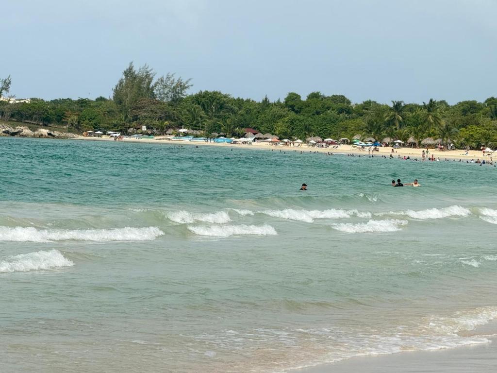 a group of people swimming in the water at a beach at STEPS TO THE BEACH 2 Stunning condo 4 min walk to Bibijagua Beach and Catamarans in Punta Cana