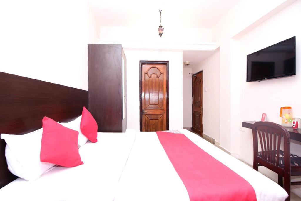 a bedroom with a large bed with red and purple pillows at Hotel O Dwarika Inn in Jabalpur