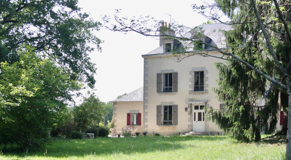 a large white house with red doors and trees at Demeure Les ragottières in Le Plessis