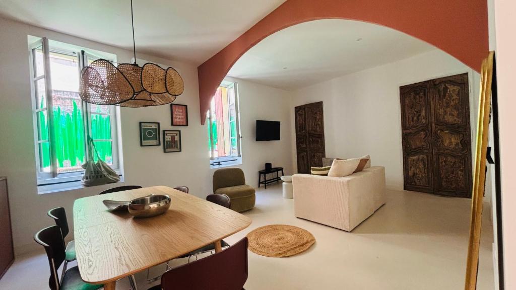 a living room with a wooden table and a room with a couch at Appartement arche centre historique in Narbonne