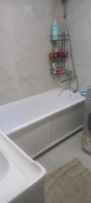 a white bath tub in a bathroom with a shelf at NurNomad 2 in Balykchy