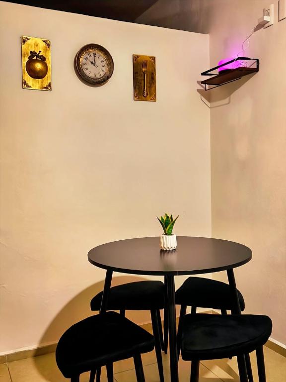 a table with four chairs and a clock on the wall at Departamento Refugio Verde in Palenque