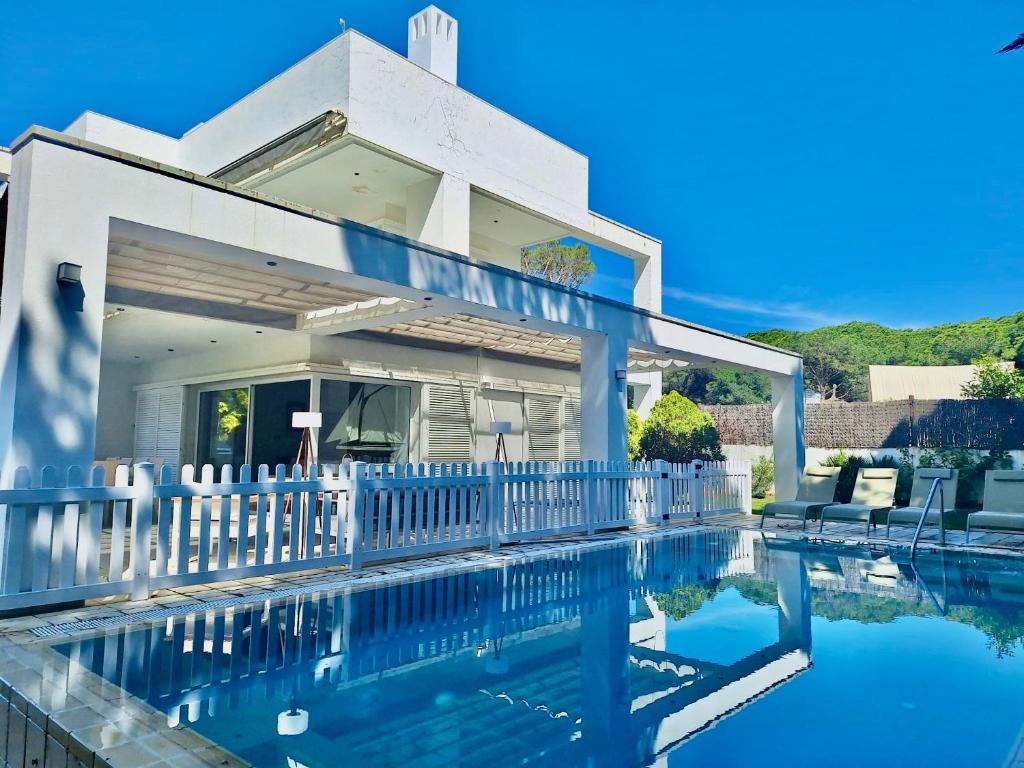 a house with a swimming pool and a white fence at Villa Pinares de Roche - Piscina privada - Playa a 6 min in Roche