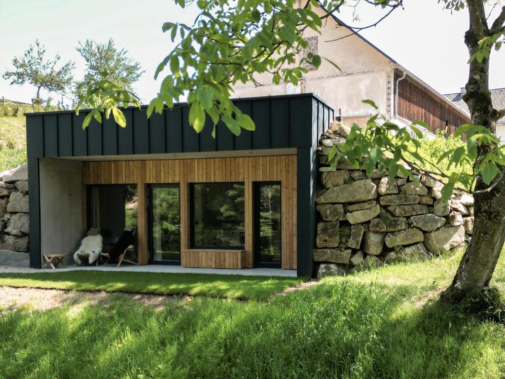 a house with a black roof and a stone wall at Tiny House Urlaub in Ybbsitz