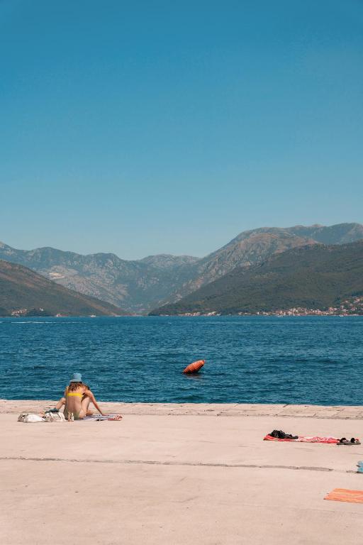 a person laying on a beach next to the water at BlueWave Apartments in Tivat