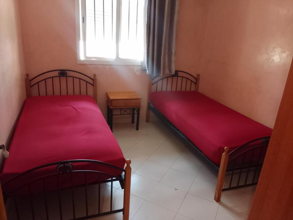 two beds in a small room with a window at ma chambre in Casablanca