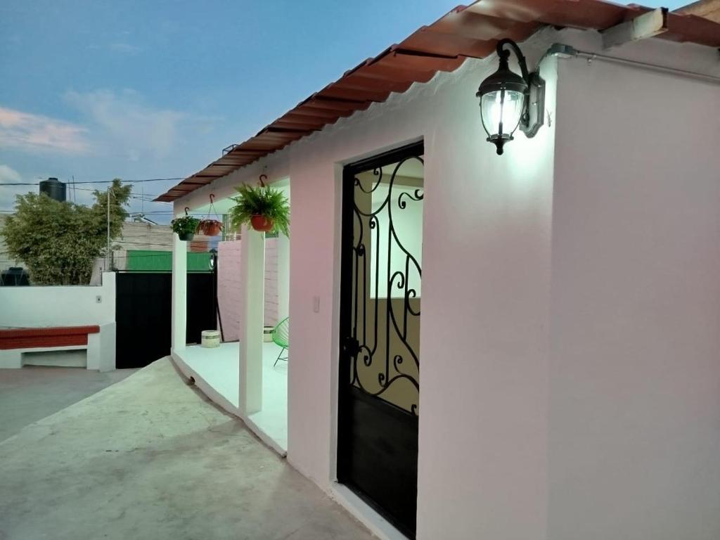 a white house with a black door and a lamp at Casa San Rafael in Oaxaca City