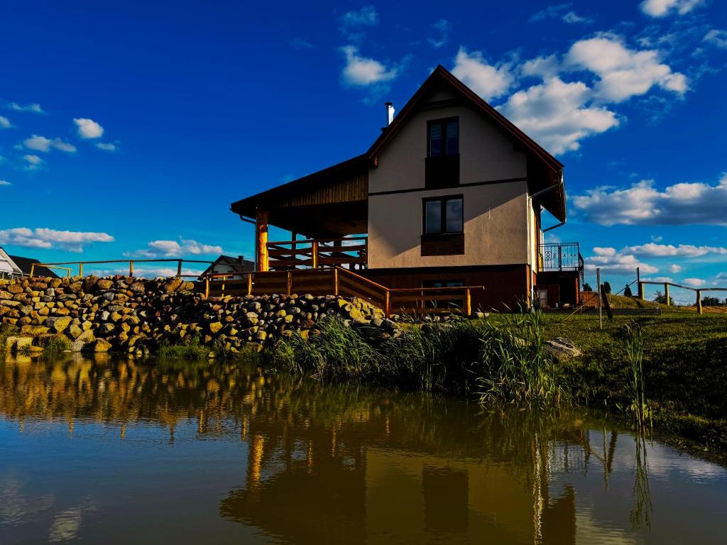 a house on a hill next to a body of water at Domek nad Oczkiem Wodnym in Giżycko
