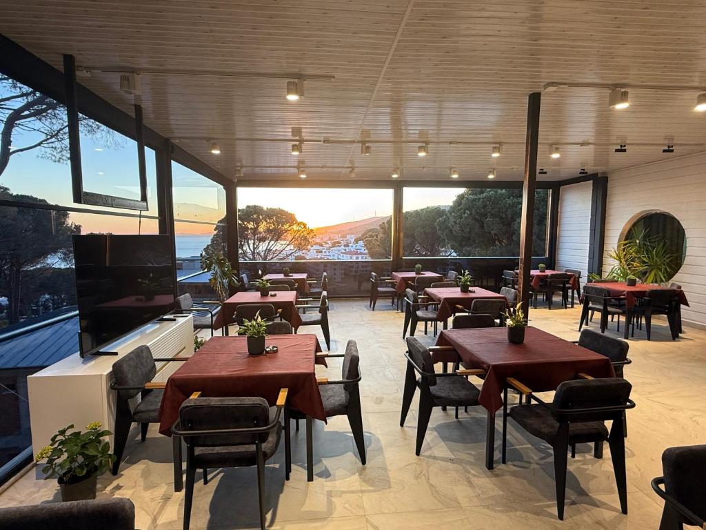a restaurant with tables and chairs and a large window at Çamra Otel in Armutlu