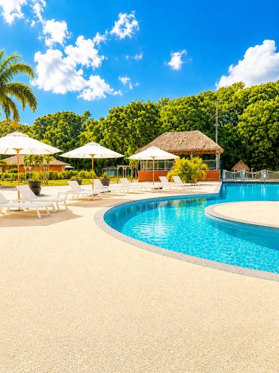 a resort swimming pool with umbrellas and chairs at La Bulle de Maloma - Piscine réouverte, Cocon pour Duo, Plage à 2 min in Grand-Bourg