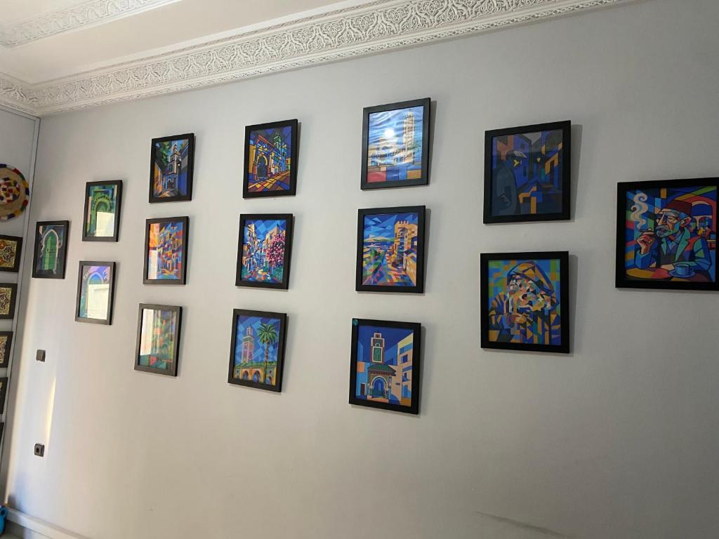 a wall with a bunch of framed paintings on it at TANJALUCIA HOSTeL in Tangier