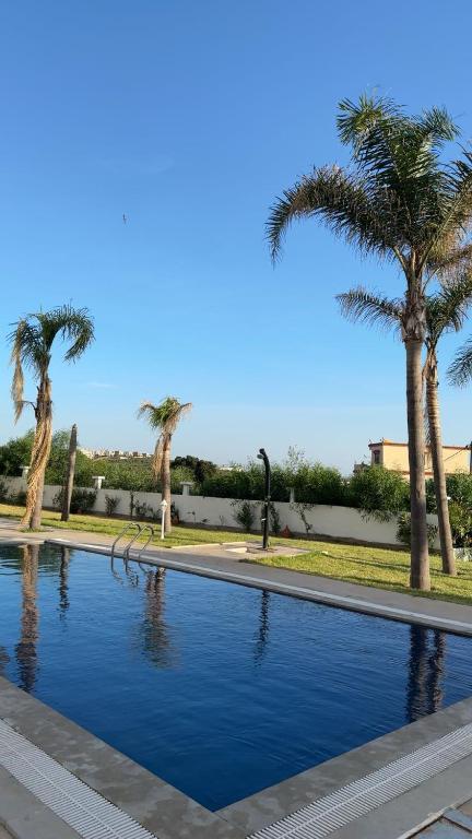 a swimming pool with palm trees in the background at Naders in Tangier