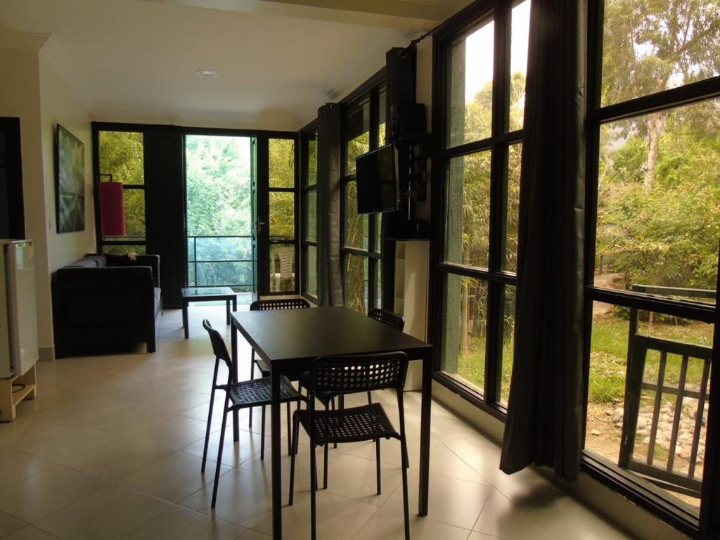 a dining room with a table and chairs and windows at La Maison Nature Relax, Explore, Unwind in Asguine