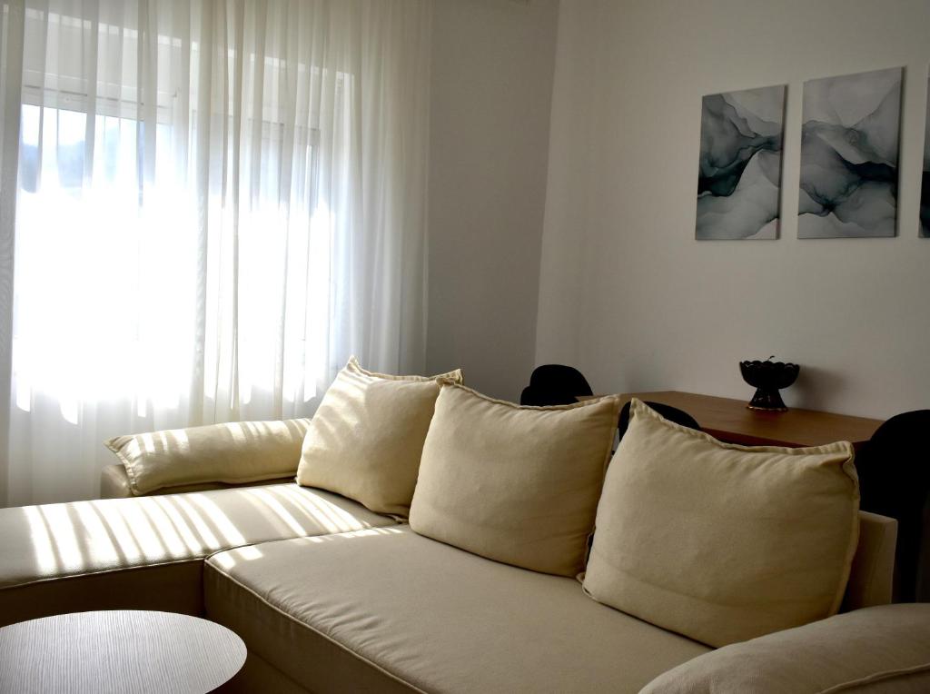 a living room with a white couch and a window at FAME Apartment - Permet in Përmet