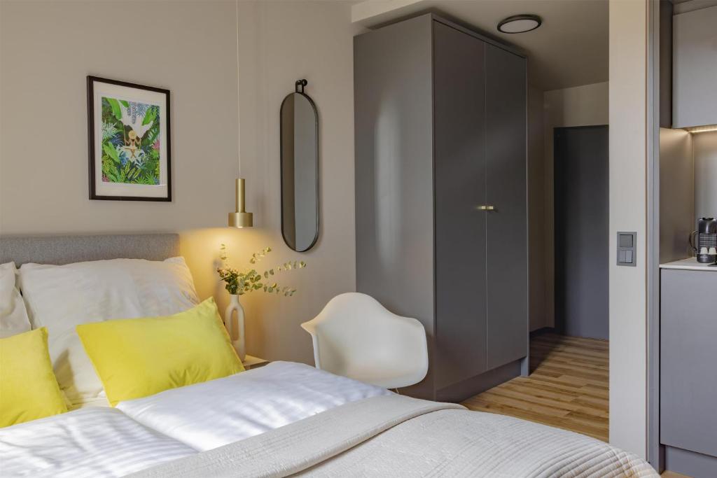 a bedroom with a bed with yellow pillows and a chair at ipartment Leverkusen @HOME by Best Western in Leverkusen