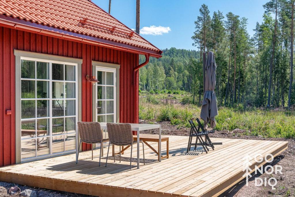 a red cabin with a table and chairs on a deck at Bluebirch Cabin in Tällberg