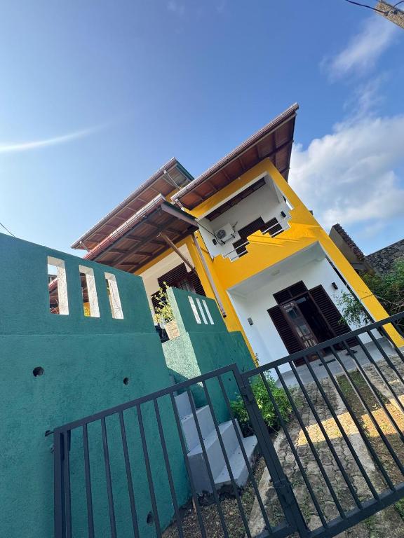 a yellow and green house with a black fence at senlin villa in Galle